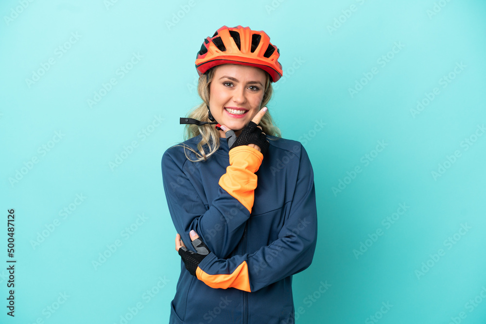 Young cyclist woman isolated on blue background happy and smiling Young cyclist woman isolated on blue background happy and smiling