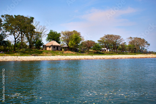 Foto día soleado en un río con una cabaña en la orilla del rio rodeado de arboles en