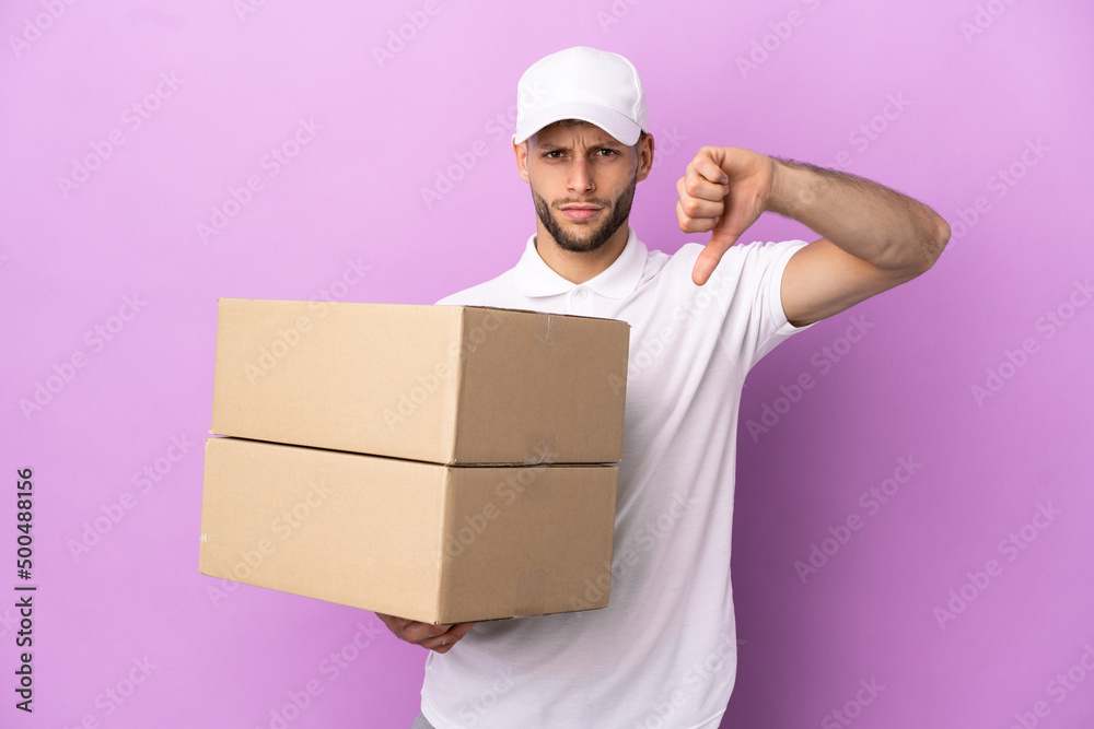 Delivery caucasian man isolated on purple background showing thumb down with negative expression Delivery caucasian man isolated on purple background showing thumb down with negative expression