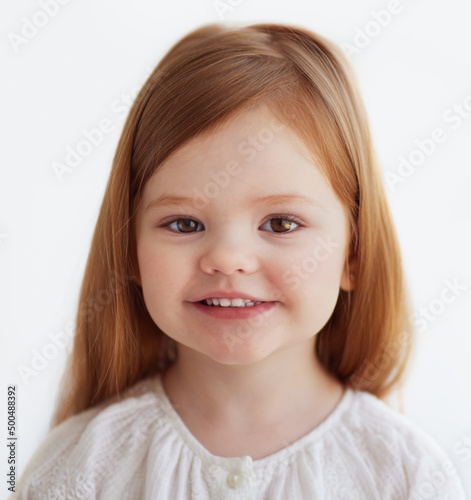 portrait of smiling redhead baby girl, 3 years old