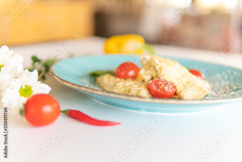 Scrambled eggs with bacon tomatoes and herbs on a white table