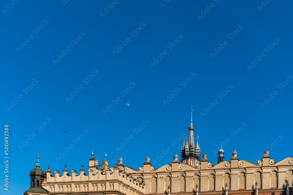 Moon in the blue sky and a dove over the historical center of Old Krakow on a sunny day, Poland, free copy space. Main market in Krakow