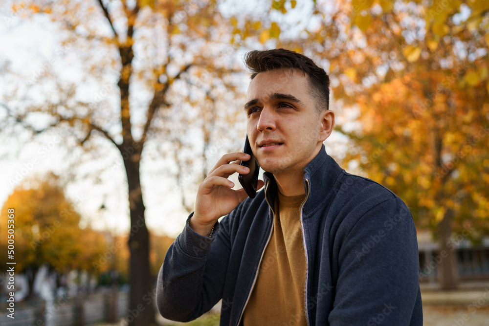 Young caucasian man standing outdoor alone in autumn evening making a phone call smiling happy real people copy space Young caucasian man standing outdoor alone in autumn evening making a phone call smiling happy real people copy space