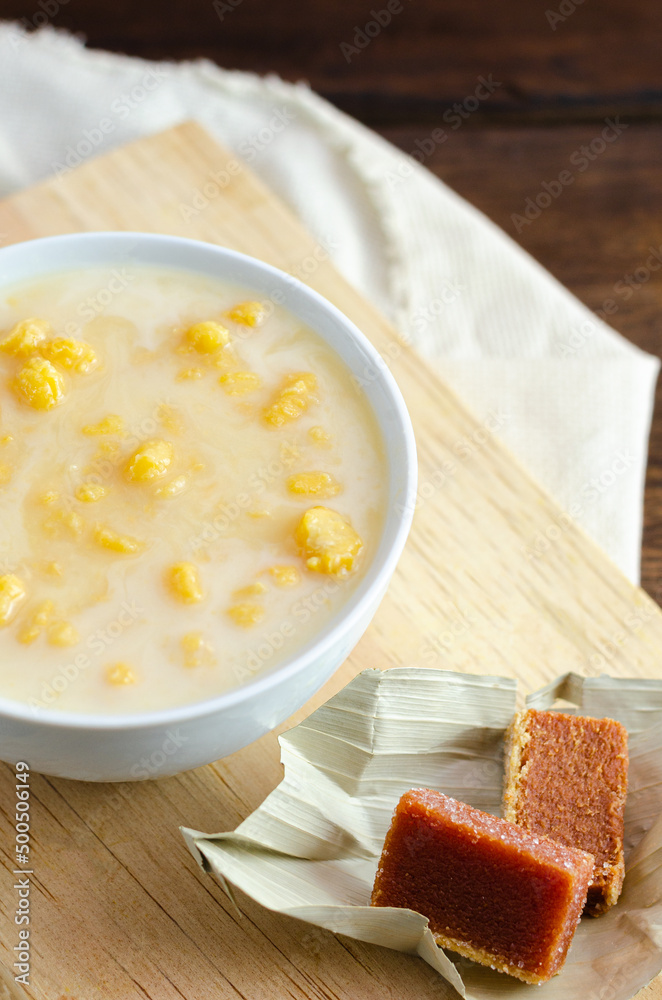 Traditional Colombian food called mazamorra,based on cooked corn dissolved in milk,accompanied with sweet guava(called a bocadillo). Dark wooden background. Close up. 