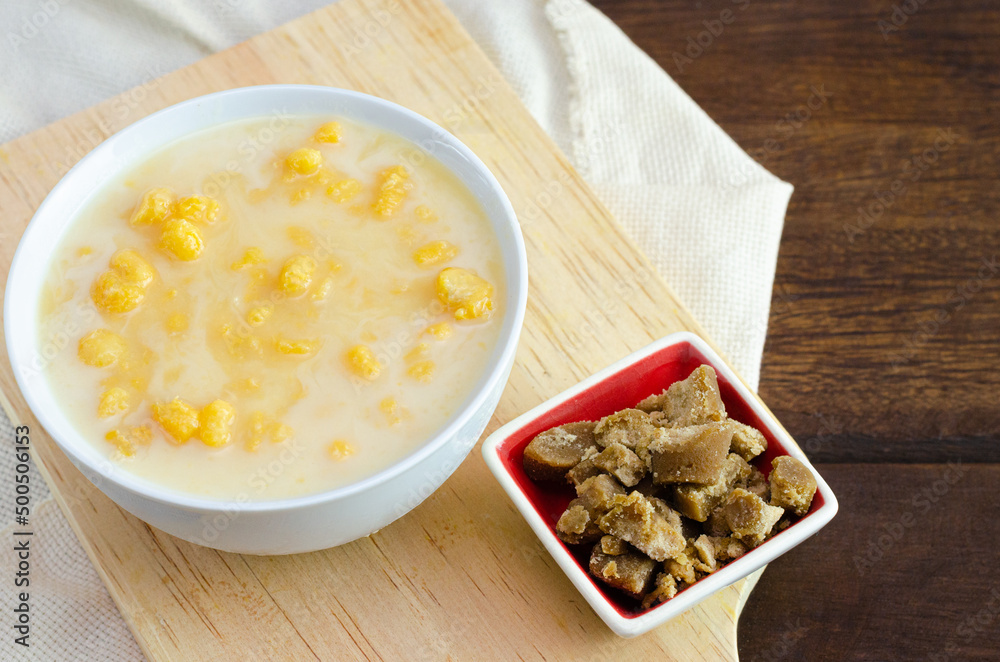 Traditional Colombian food called mazamorra,based on cooked corn dissolved in milk,accompanied with panela in pieces (sweet from sugar cane). Dark wooden background. Traditional Colombian food called mazamorra,based on cooked corn dissolved in milk,accompanied with panela in pieces (sweet from sugar cane). Dark wooden background.