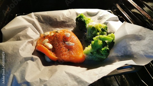 A healthy dinner preparetion in oven. Salmon and brocoli. selective focus photo