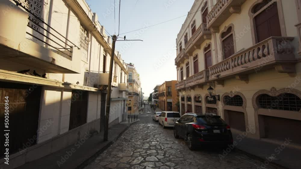 Emiliano Tejera street in the old colonial city at dawn. Paving stones on the road and parked cars. Santo Domingo, Dominican Republic Emiliano Tejera street in the old colonial city at dawn. Paving stones on the road and parked cars. Santo Domingo, Dominican Republic