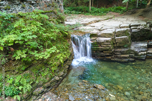 Amazing landscape of beautiful waterfall on mountain river with white foamy water falling down from rocky cliff in summer rainforest