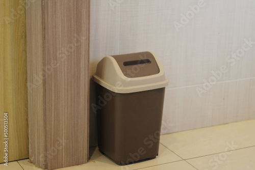 The trash can is on the wall with a wooden background