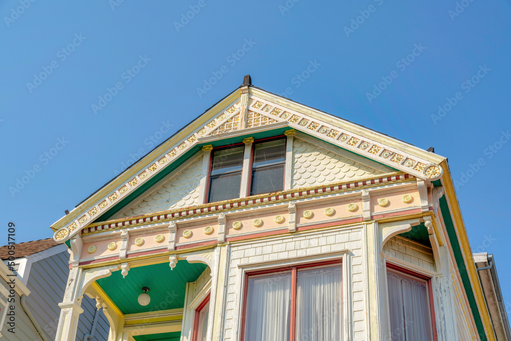 Low angle view of a house with ornate trims and yellow shingles wall sidings