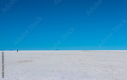 foto minimaslista de uma pessoa no salar Uyuni, , ceu azul e deserto branco de sal