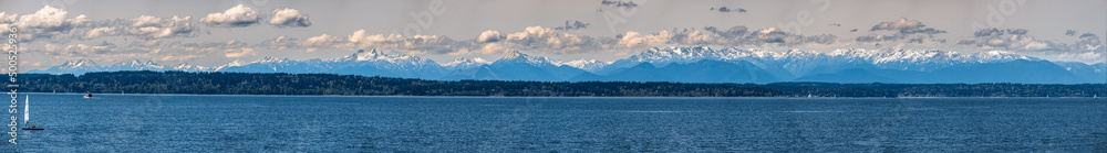 A panorama of the Olympic Mountain range seen across from Puget Sound on a sunny day
