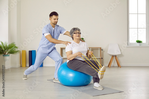 Male physiotherapist do exercises workout with elderly woman patient in physio medical clinic. Therapist doctor help old grandmother recover after injury or trauma. Mature rehabilitation.