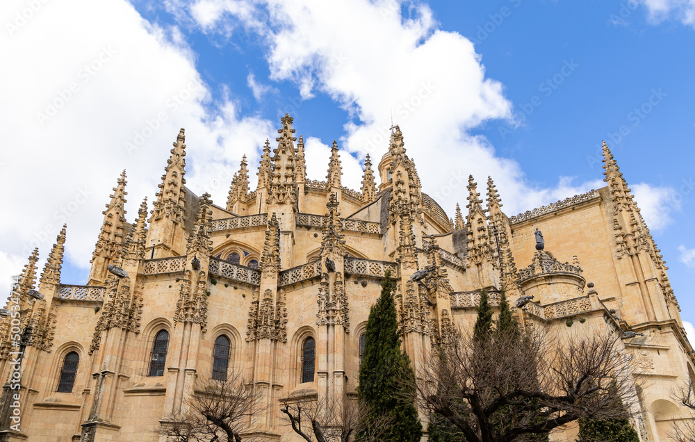 views of the gothic and renaissance cathedral of Segovia with tourists walking under its arches in Segovia