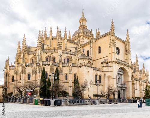 views of the gothic and renaissance cathedral of Segovia with tourists walking under its arches in Segovia