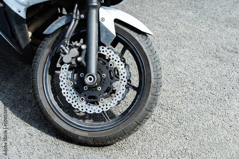 Obraz premium The front wheel of a motorcycle with a lightweight brake disc. Close-up