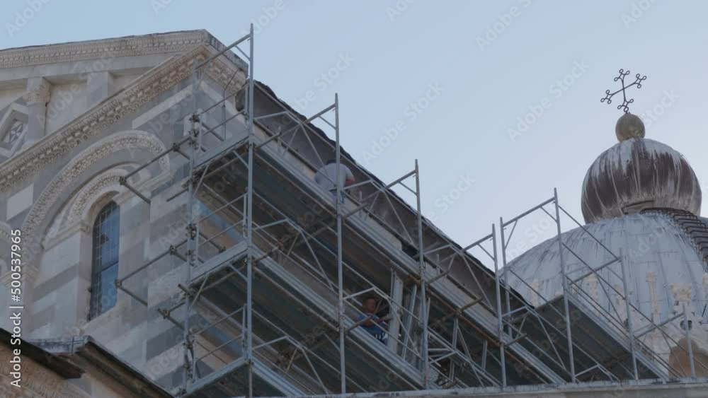 Construction workers working on high scaffold during facade renovations of a church in Pisa (Ialy)