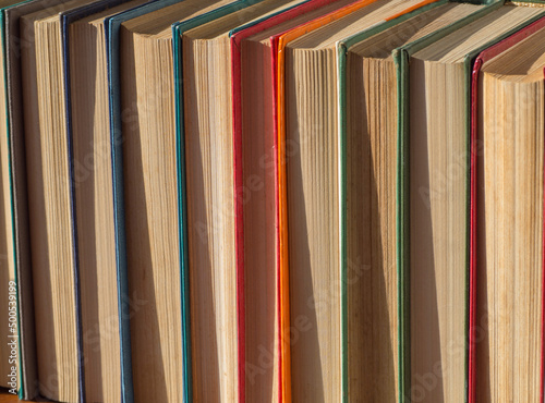 Old hardcover books on a wooden table. Yellow pages of old books on the shelf. A collection of rare books. Colorful books. Abstract concept of knowledge, education, training and literature