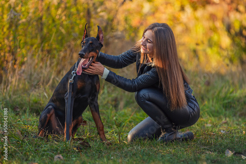 girl sitting near a doberman dog breed in nature © zokov_111