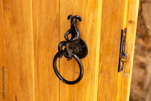 Vintage metal door knocker on the restored wooden gate
