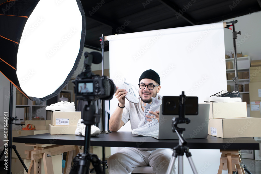 Young attractive Asian man blogger or vlogger looking at camera reviewing product. Modern businessman using social media for marketing. Business online influencer on social media concept. Young attractive Asian man blogger or vlogger looking at camera reviewing product. Modern businessman using social media for marketing. Business online influencer on social media concept.