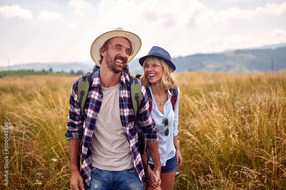 A young couple is in a good mood while walking a meadow. Hiking, nature, relationship, together A young couple is in a good mood while walking a meadow. Hiking, nature, relationship, together