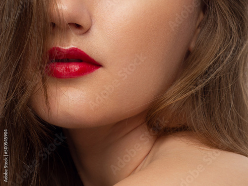 The macro photo of the closed female mouth. Chubby lips with red lipstick show a fashionable make-up and increase in lips. Cosmetology  Spa  cosmetics