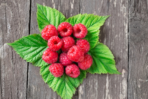 raspberry with leaves on wooden table.