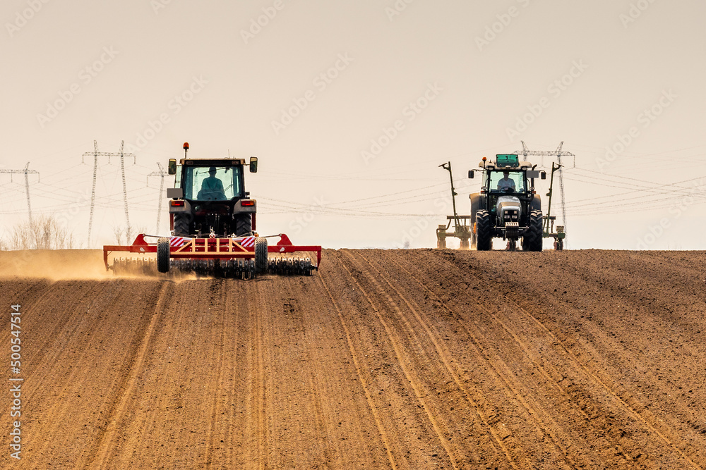 Fototapeta premium Tractor at agricultural farm field cultivating land
