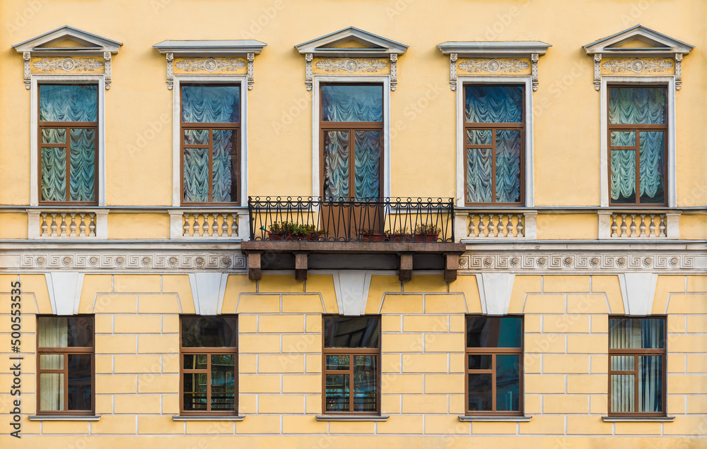 Balcony and many windows in a row on the facade of the urban historic apartment building front view, Saint Petersburg, Russia
