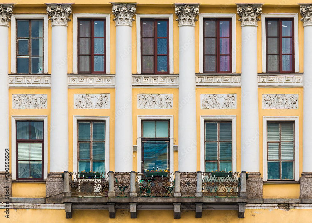 Balcony and many windows in a row on the facade of the urban historic apartment building front view, Saint Petersburg, Russia
