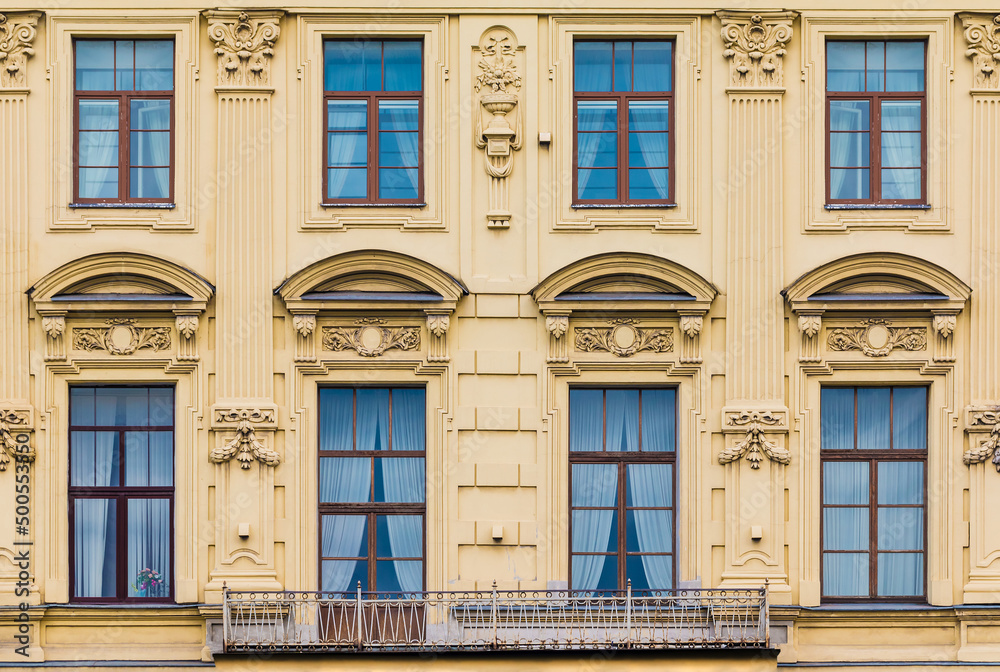Balcony and several windows in a row on the facade of the urban historic apartment building front view, Saint Petersburg, Russia
