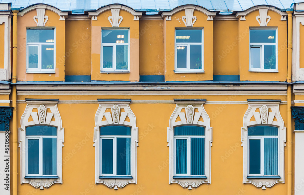 Fototapeta premium Several windows in a row on the facade of the urban historic apartment building front view, Saint Petersburg, Russia 