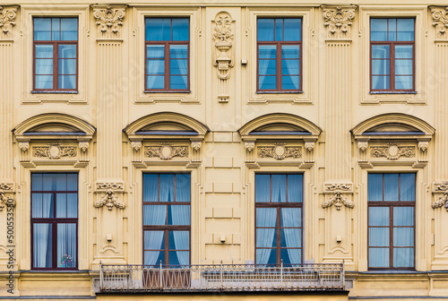 Balcony and several windows in a row on the facade of the urban historic apartment building front view, Saint Petersburg, Russia 