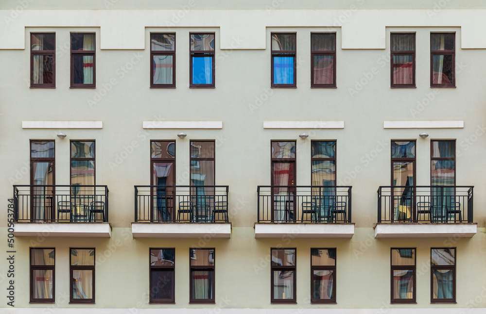 Several balconies and many windows in a row on the facade of the modern urban apartment building front view, Krasnaya Polyana, Sochi, Krasnodar Krai, Russia
