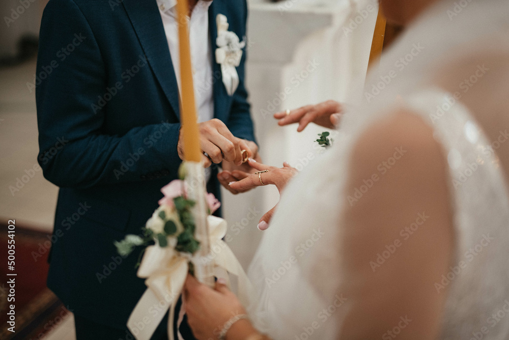 Wedding matrimony in church. Priest putting on golden wedding ring on bride finger. Wedding candles. Wedding matrimony in church. Priest putting on golden wedding ring on bride finger. Wedding candles.