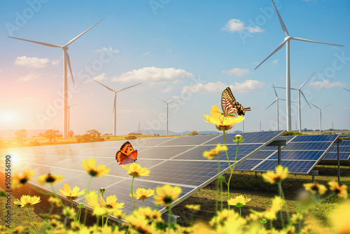 Solar power generation plant with a focus on solar panels with flowers and butterfly in the foreground. Concept of conservation of nature and the environment. photo