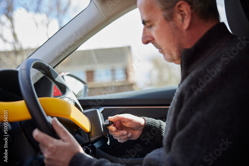 Obraz na płótnie Mature Man Fitting Manual Steering Wheel Lock In Car