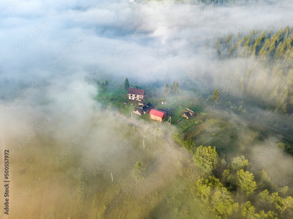 Fototapeta premium Mountain settlement in the Ukrainian Carpathians in the morning mist. Aerial drone view.