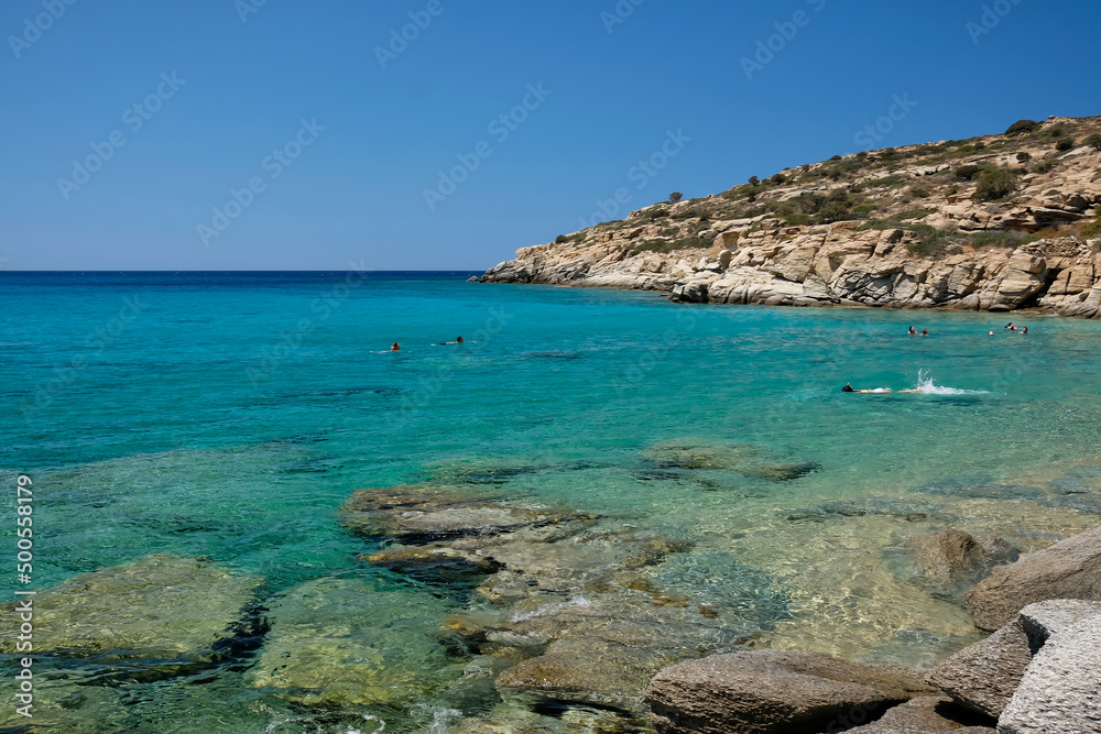 Tourists enjoying the paradisiac beach with turquoise waters and golden sand of Pikri Nero in Ios Greece Tourists enjoying the paradisiac beach with turquoise waters and golden sand of Pikri Nero in Ios Greece