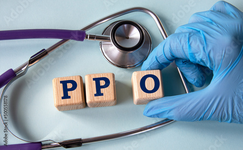 A hand in a medical glove puts cubes with the abbreviation PPO on the background of a stethoscope photo