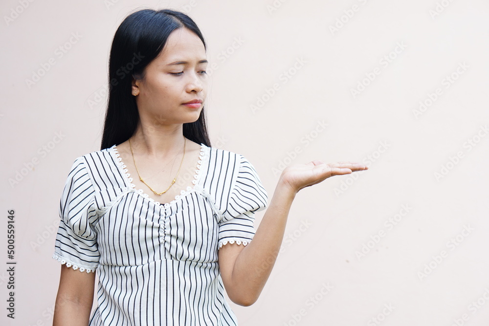 Young woman over isolated gray background holding fantasy copyspace on palm to insert ad. Young woman over isolated gray background holding fantasy copyspace on palm to insert ad.