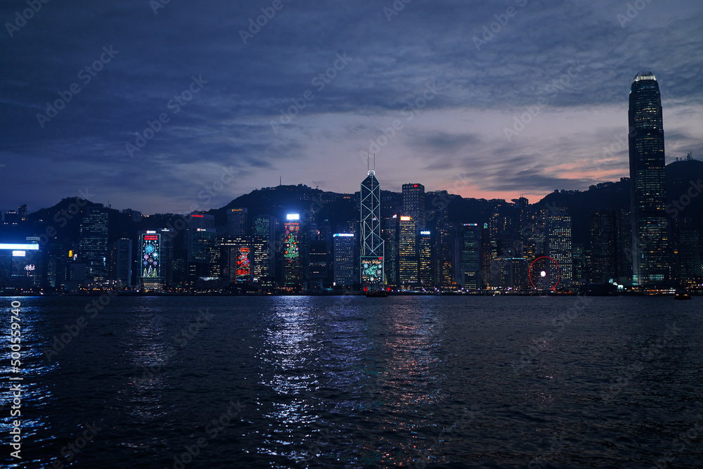 Central business district  Hong Kong with a sunset dawn sky above the harbour at night time.