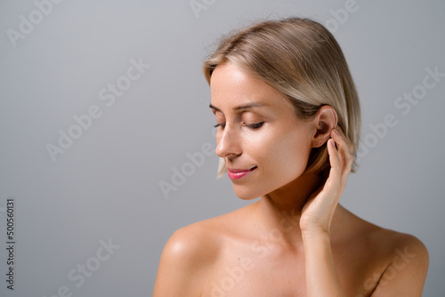 Natural beauty. Blonde woman with healthy skin. No makeup. Grey background.