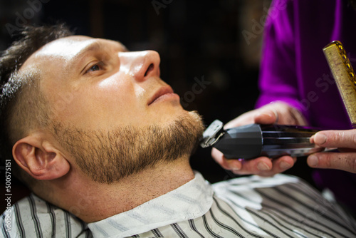 Macro Man hipster having barber shave barbershop hair machine.
