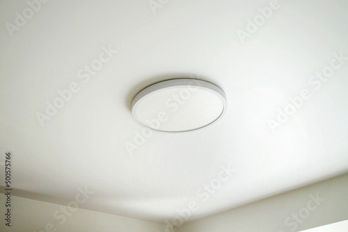 Round, minimalist, simple lamp on a white ceiling. A lamp that does not attract attention. photo