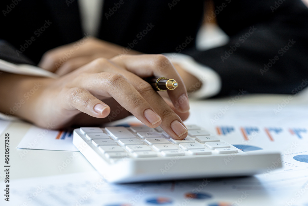 Businessman using a calculator to calculate numbers on a company's financial documents, he is analyzing historical financial data to plan how to grow the company. Financial concept.