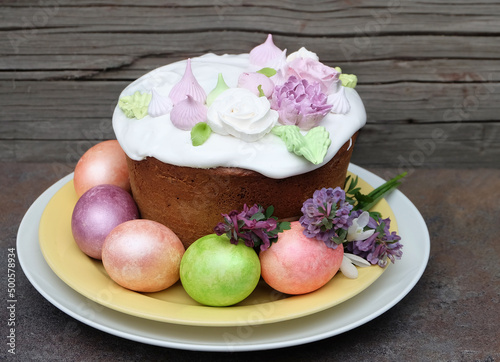 Easter cake decorated with sugar flowers and multi-colored Easter eggs in pastel colors, spring holiday composition, selective focus, horizontal orientation.