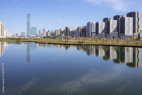 Multi-storey buildings and their reflection in the pond of Botanical Graden. Early in spring, Nur-Sultan, Kazakhstan.