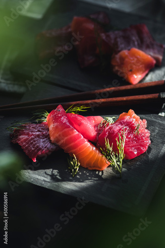 Portions of salted salmon with herbs on dark background